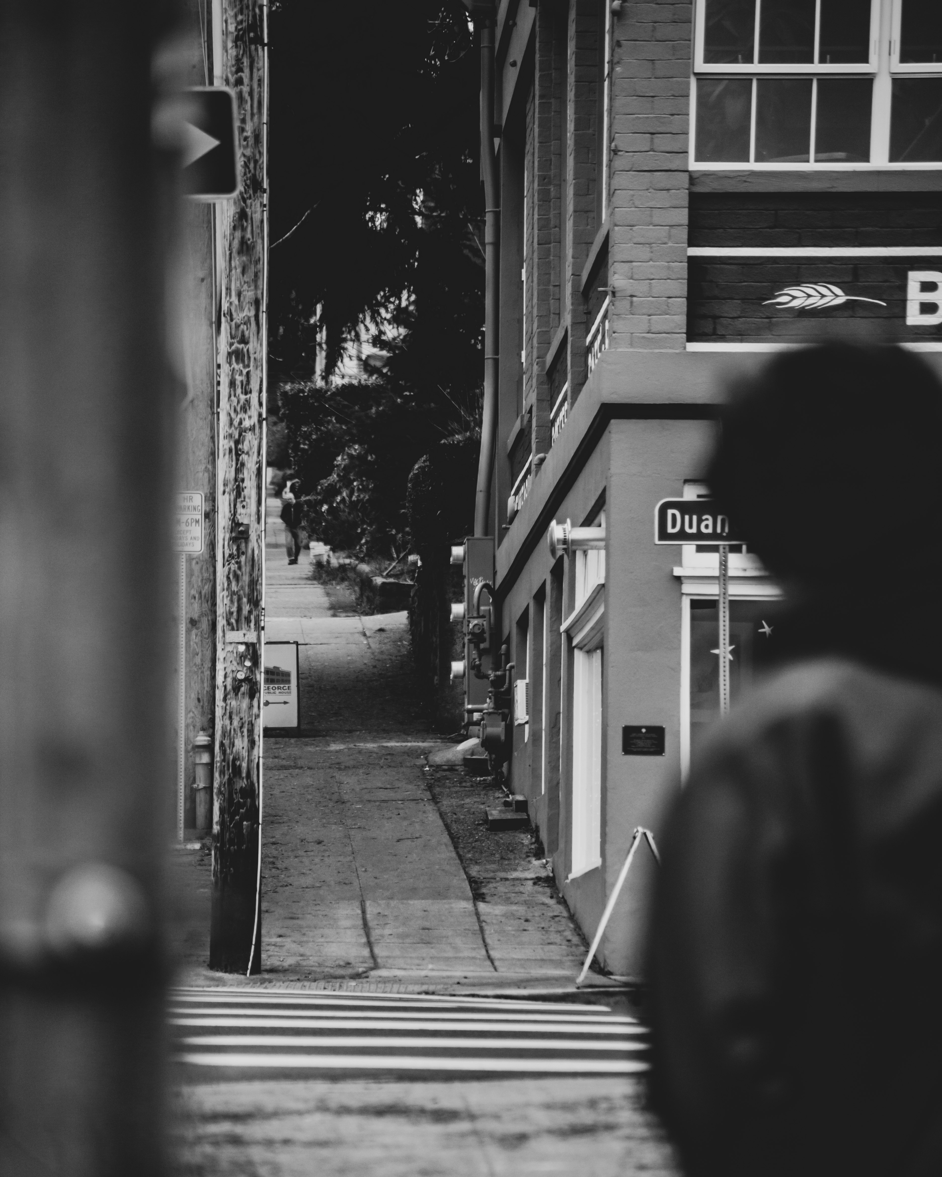 grayscale photo of man walking on sidewalk